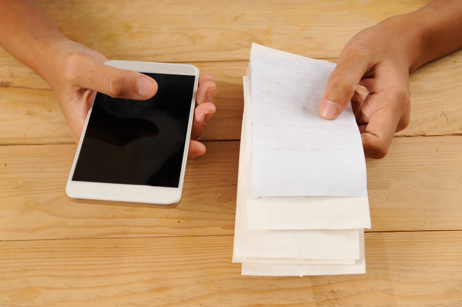 Closeup of person paying or calculating bills. Woman using smartphone. Online payment concept. Cropped view.